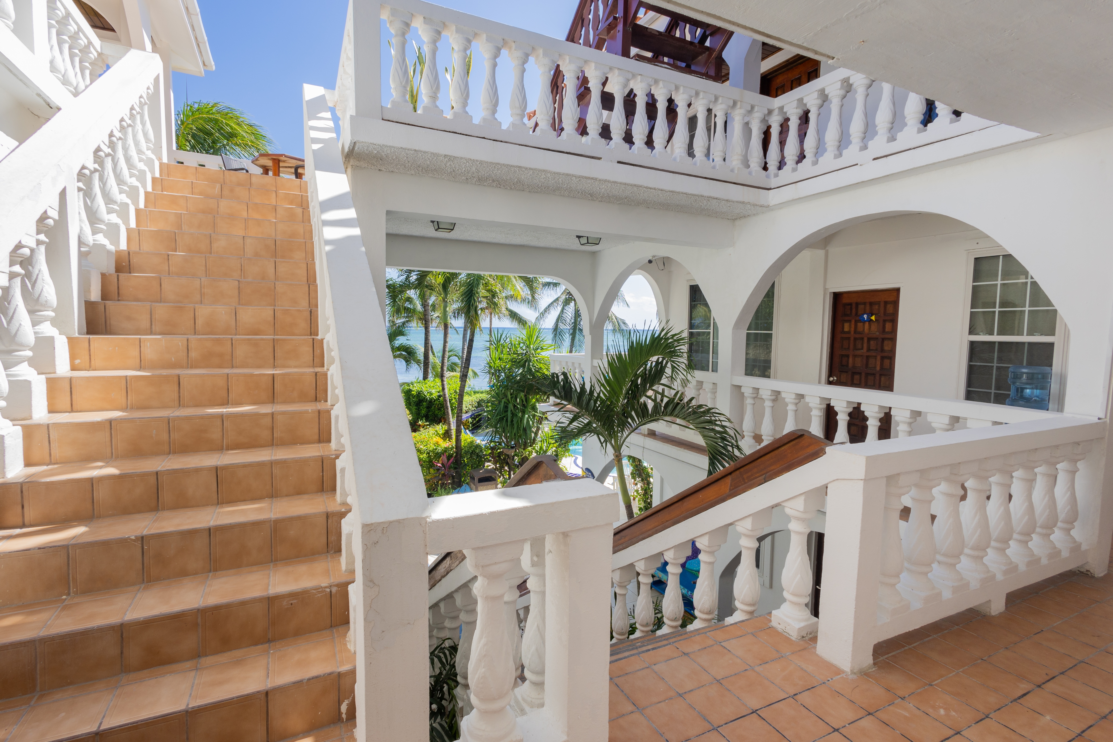 The interior of a white building with multiple levels, featuring tiled floors, white railings, and s