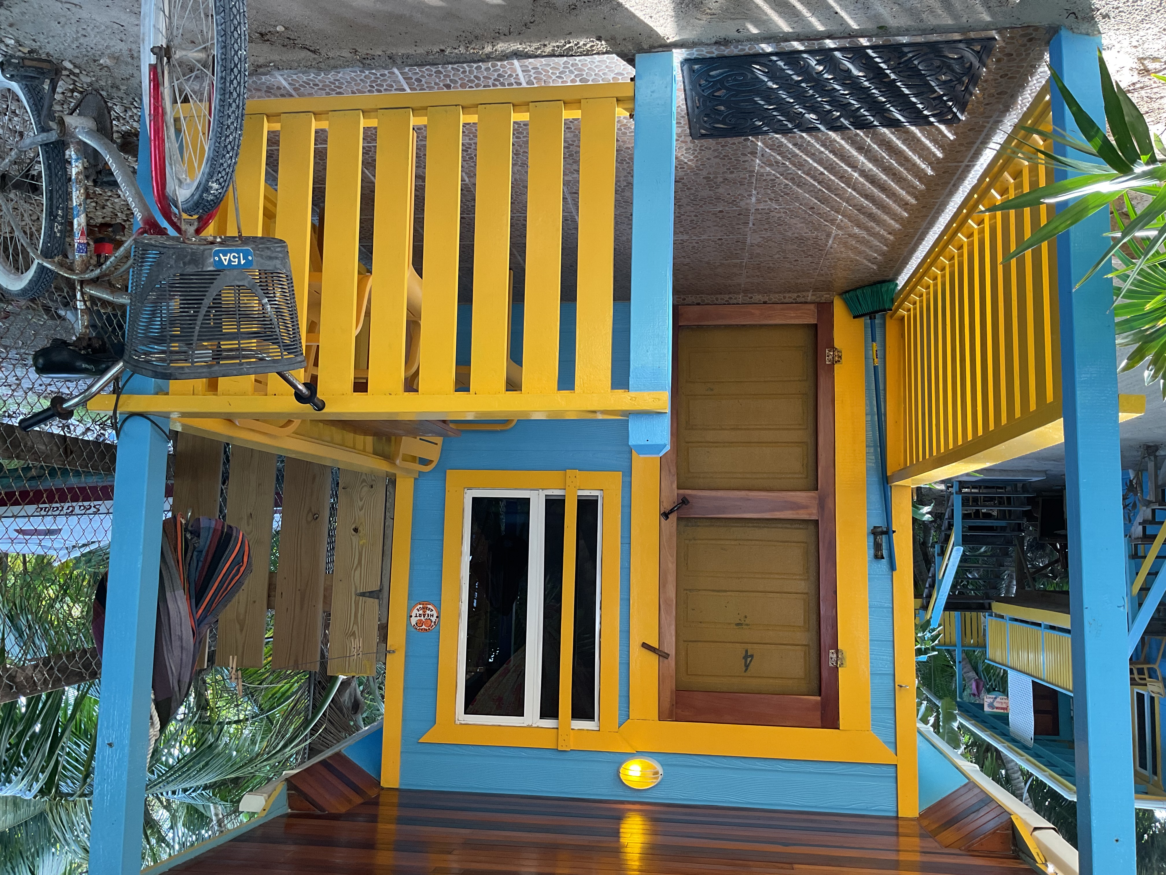 Bird's eye view of cheerfully painted blue and yellow ground-level tiny house surrounded by sand and