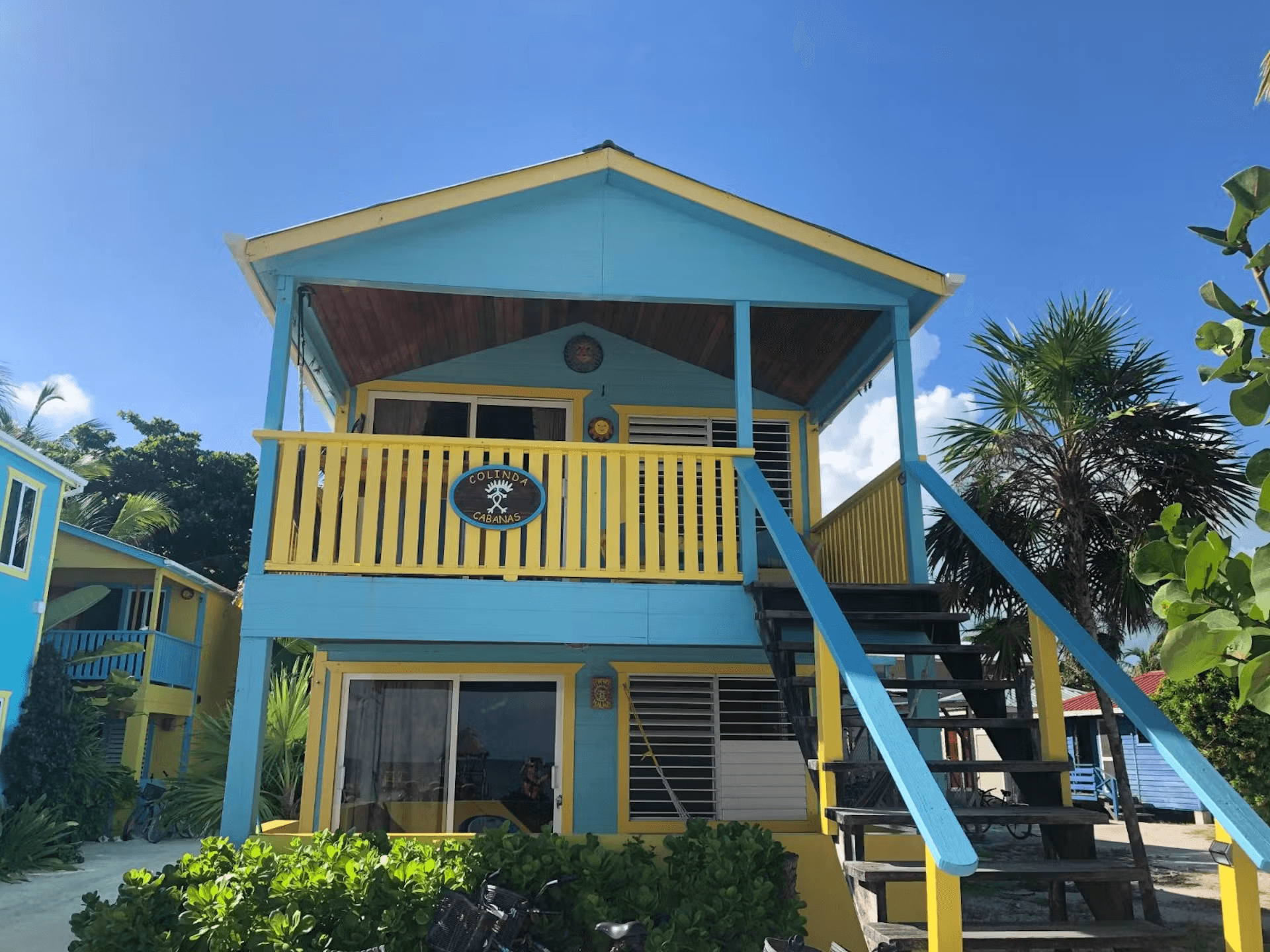 Exterior view of a colorful blue and yellow cabana with stairs leading to second level, bright blue