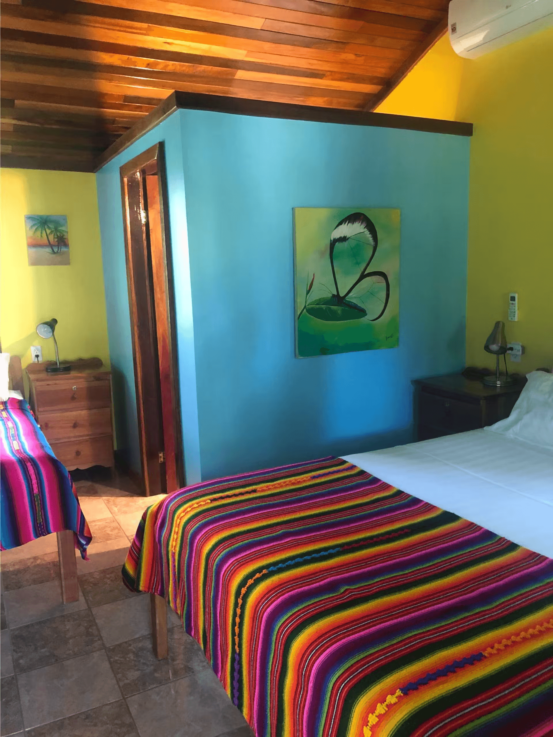 Blue and yellow painted bedroom with queen bed, dresser, nightstand, and richly finished wood ceilin