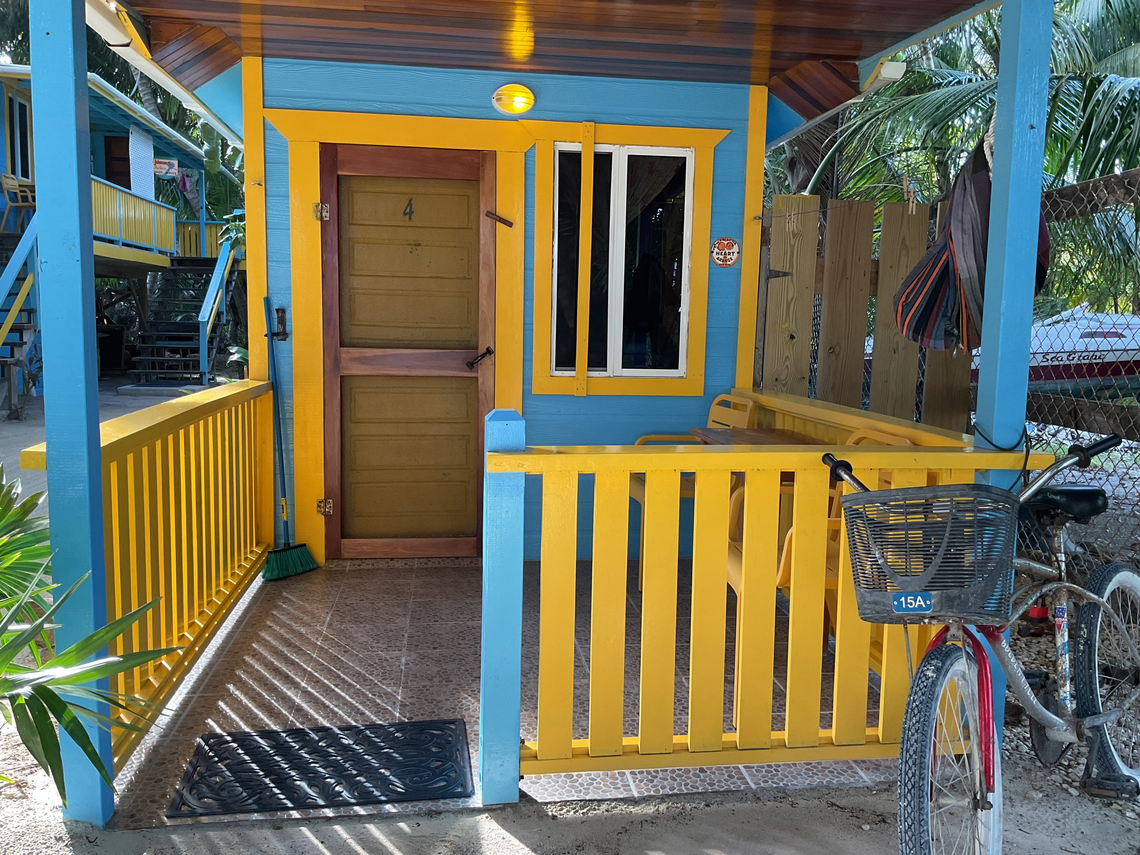 Bird's eye view of cheerfully painted blue and yellow ground-level tiny house surrounded by sand and