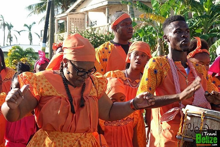 A group of individuals in vibrant orange clothing dances together during a cultural celebration. A group of individuals in vibrant orange clothing dances together during a cultural celebration.