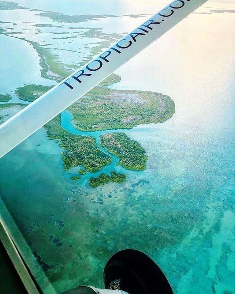 Aerial view of lush, green islands and turquoise waters captured from an airplane window.