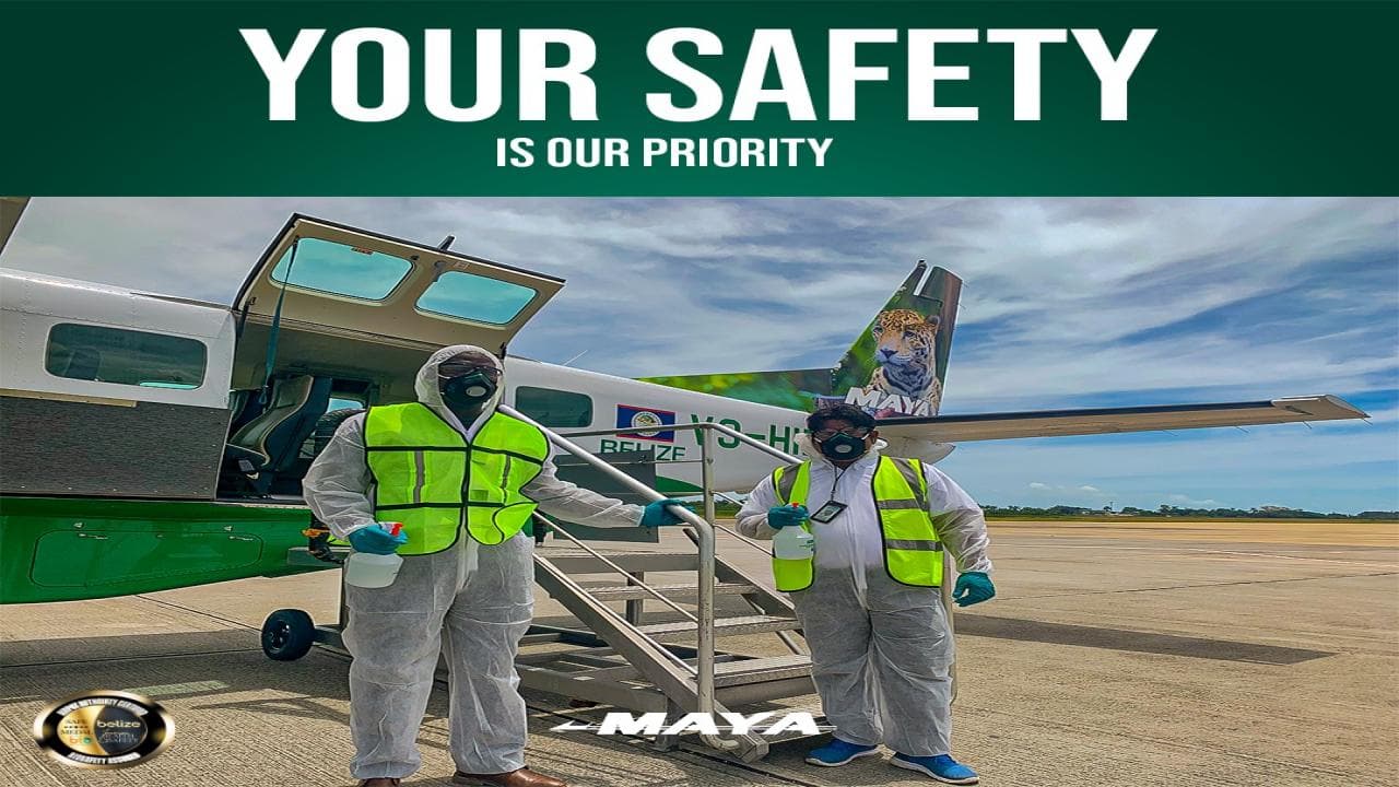 Two individuals in protective gear stand next to a small airplane, emphasizing safety measures.