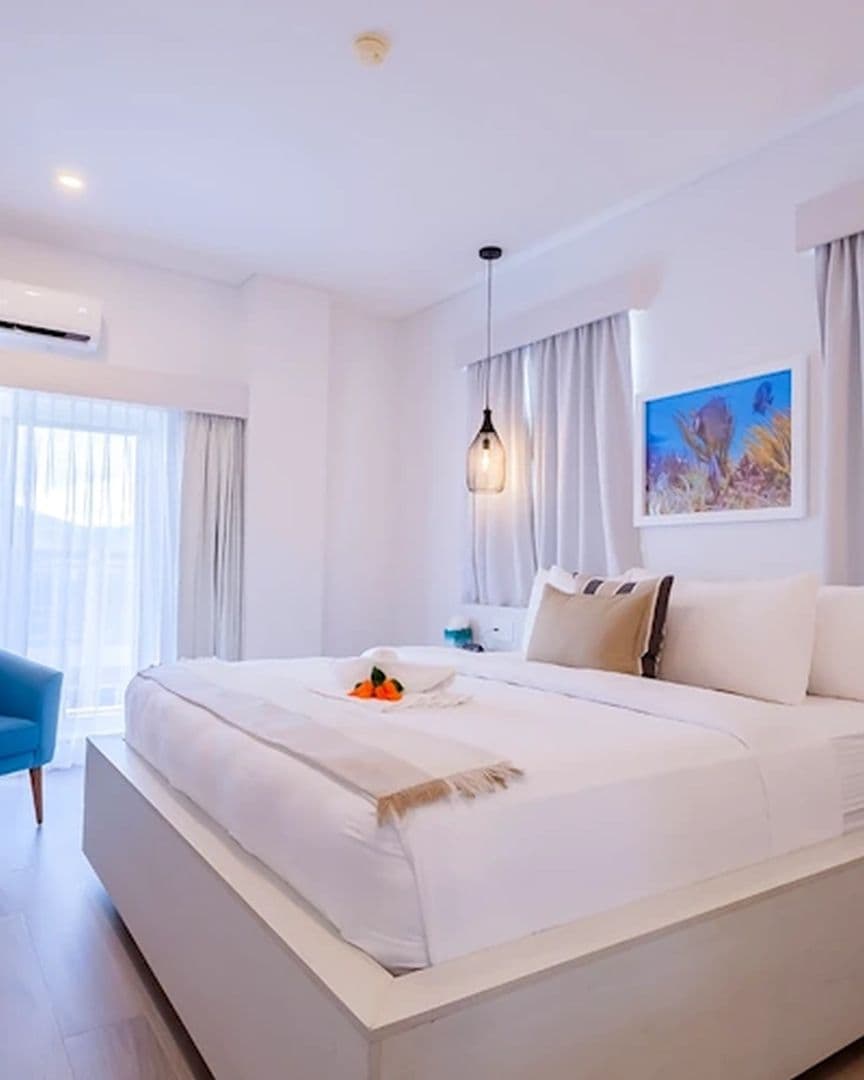Queen sized bed with white linens in white themed room